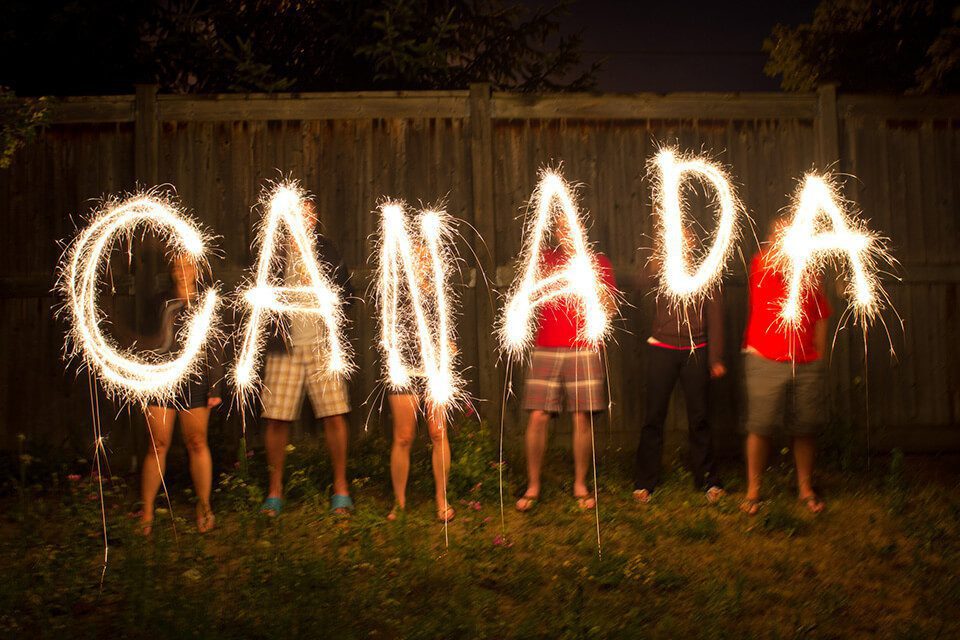 A photo of the word Canada in light-form being held up by children for the canada road trip tips section