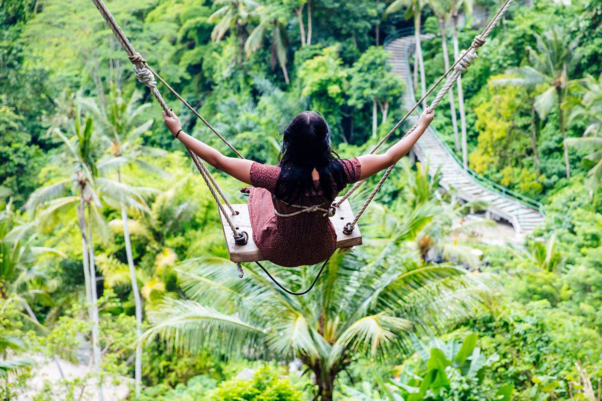 Young woman on swing in rainforest, Indonesia