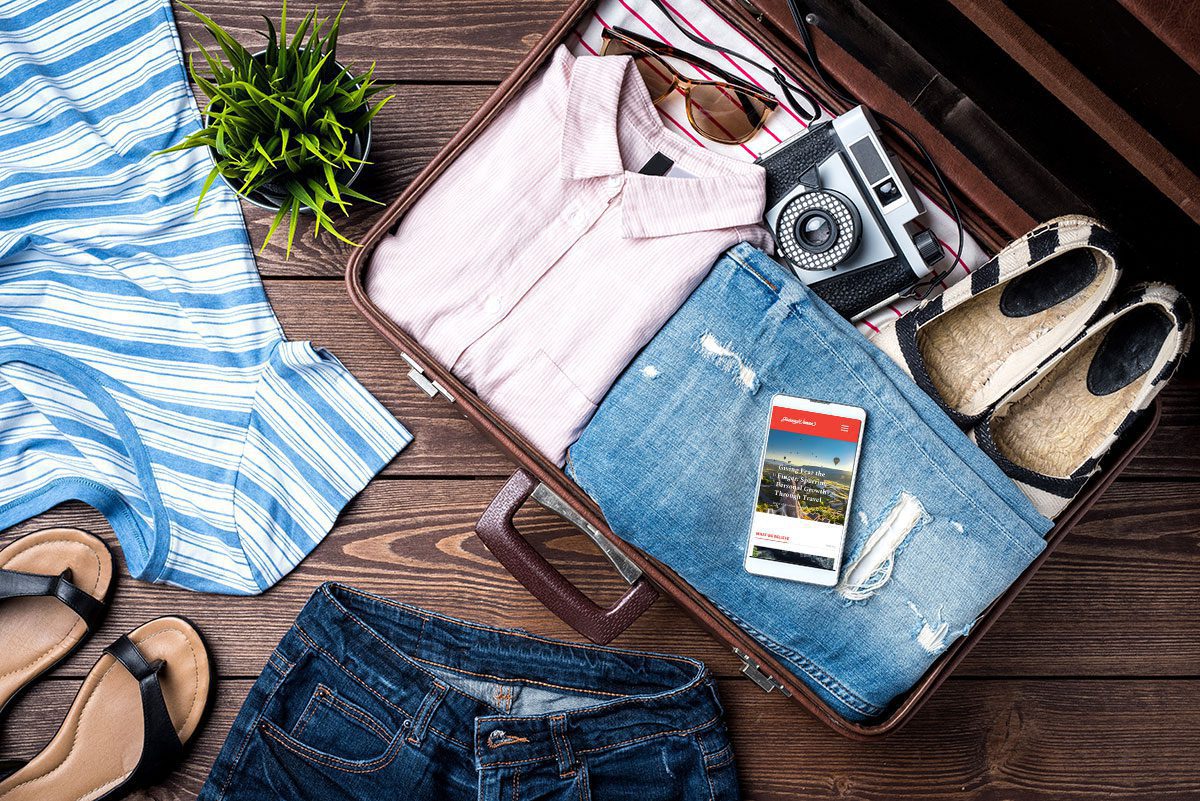 A travel ready suitcase with clothing and a smartphone for the travel clothing tips page