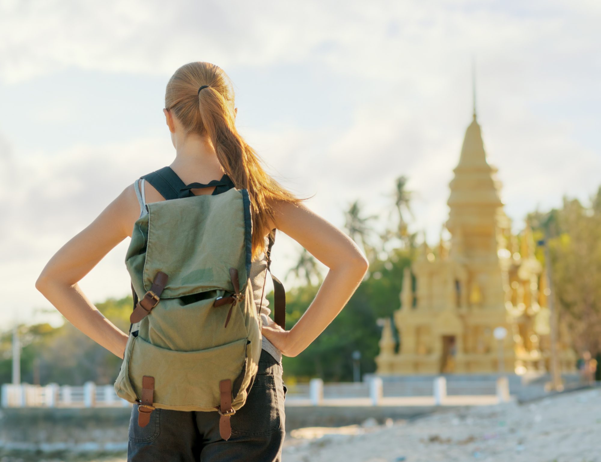 Young woman looking at golden pagoda. Hiking at Asia.