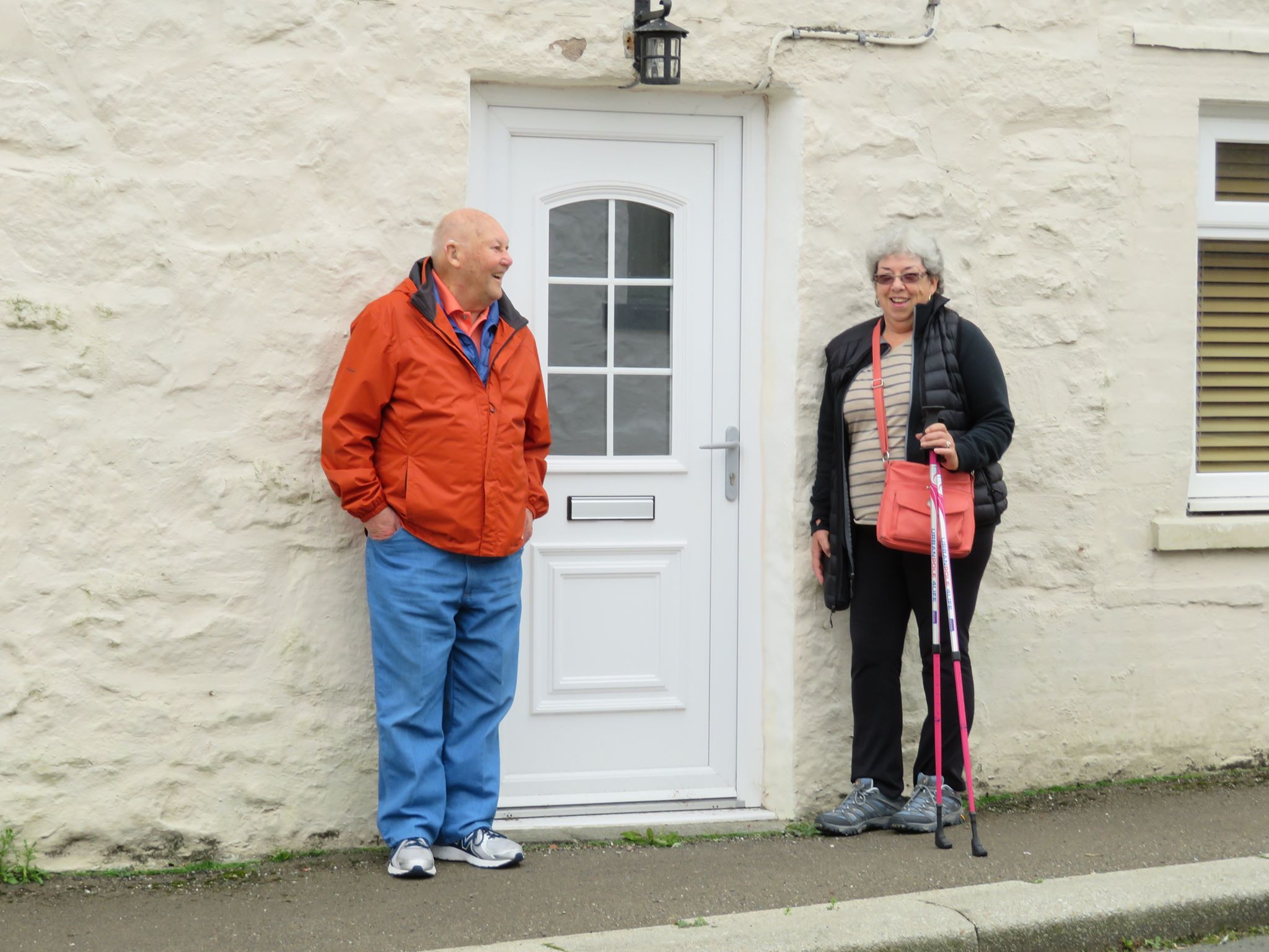 A man and woman with a walking sticks standing in front of a white door