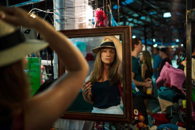 Girl trying on hat in mirror