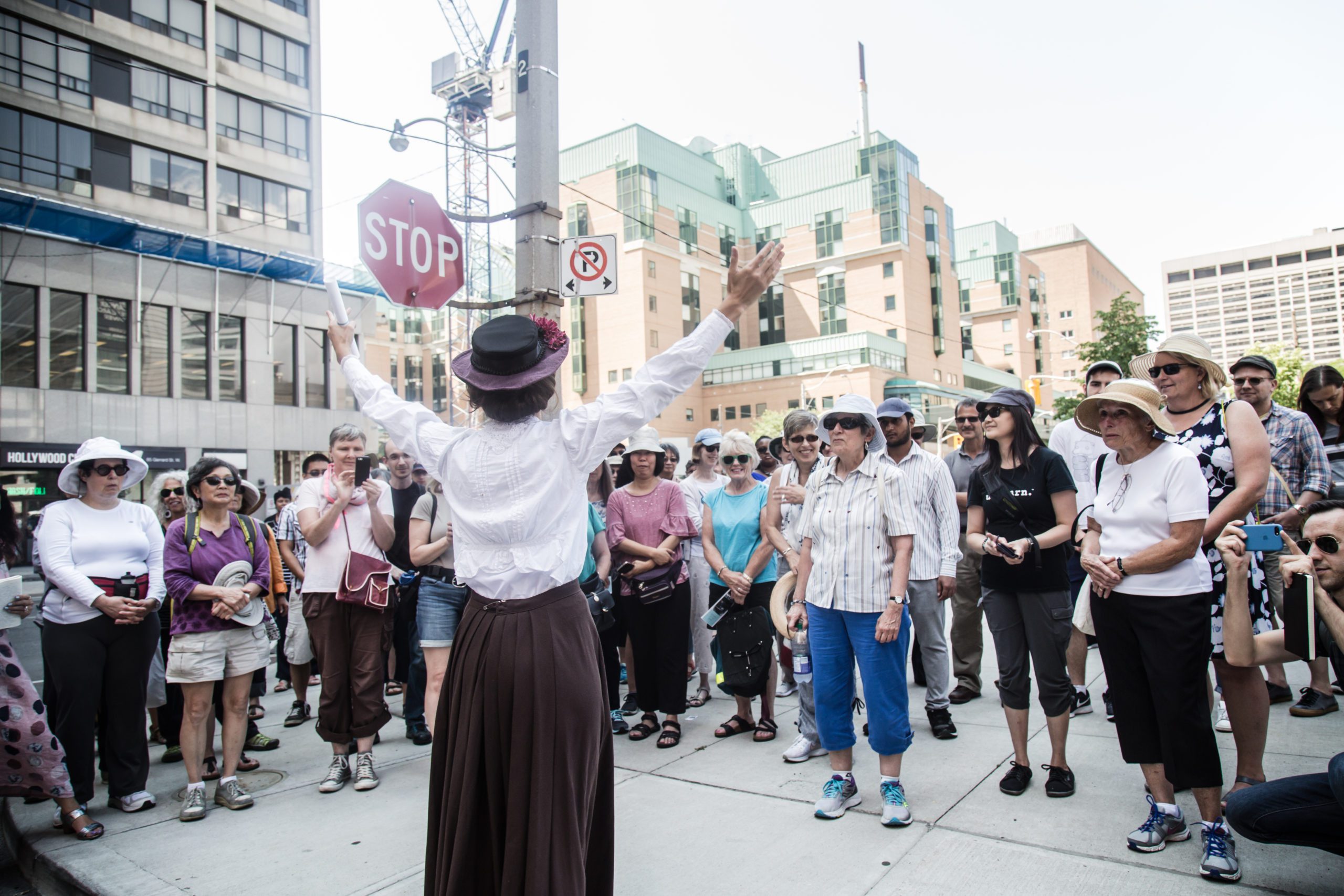 Woman in period costume talking about Women of the Ward to onlooking crowd, Toronto