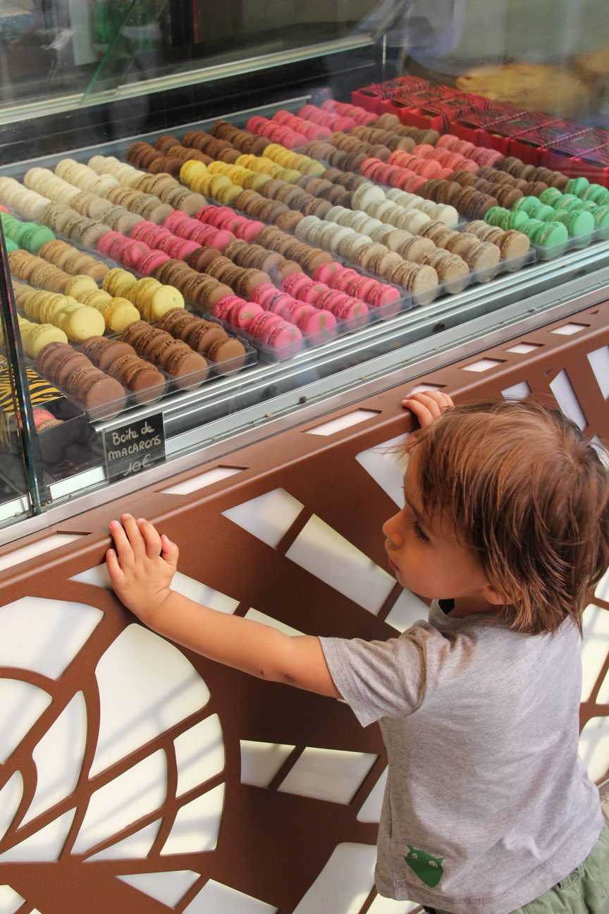 Child admires display case with colorful macaron