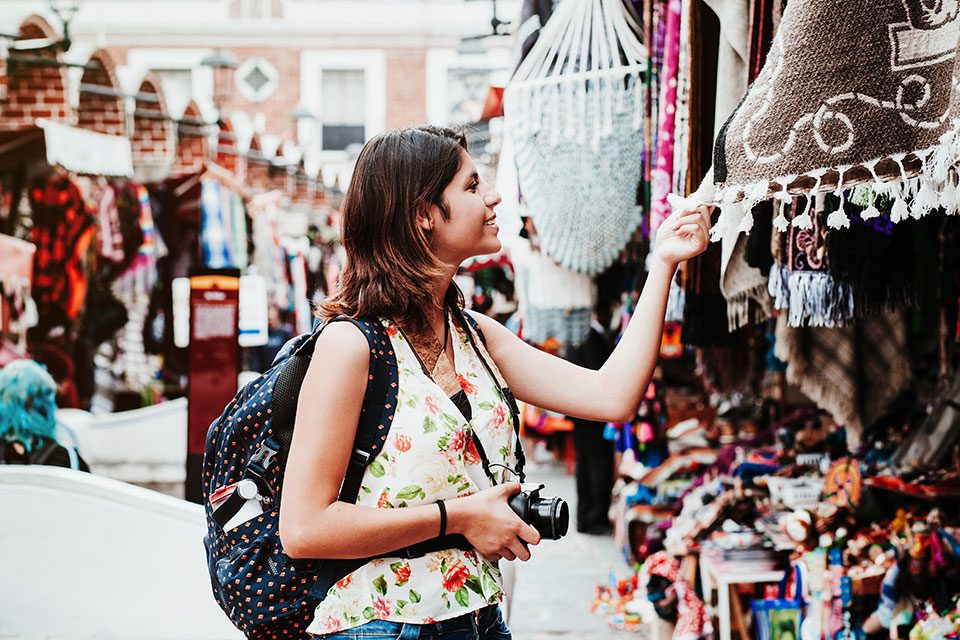 Smiling young woman perusing market stalls