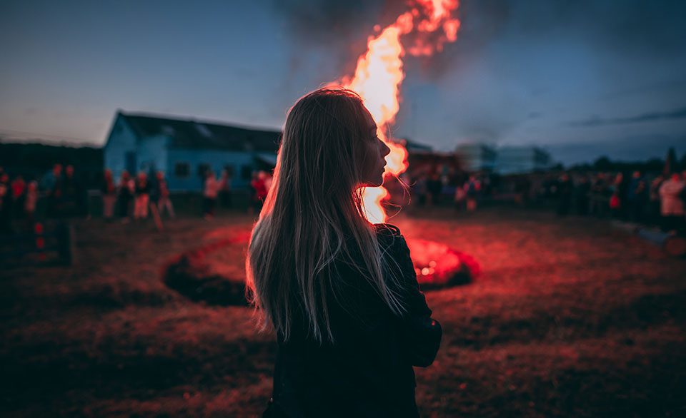 Young woman illuminated by light from a bonfire