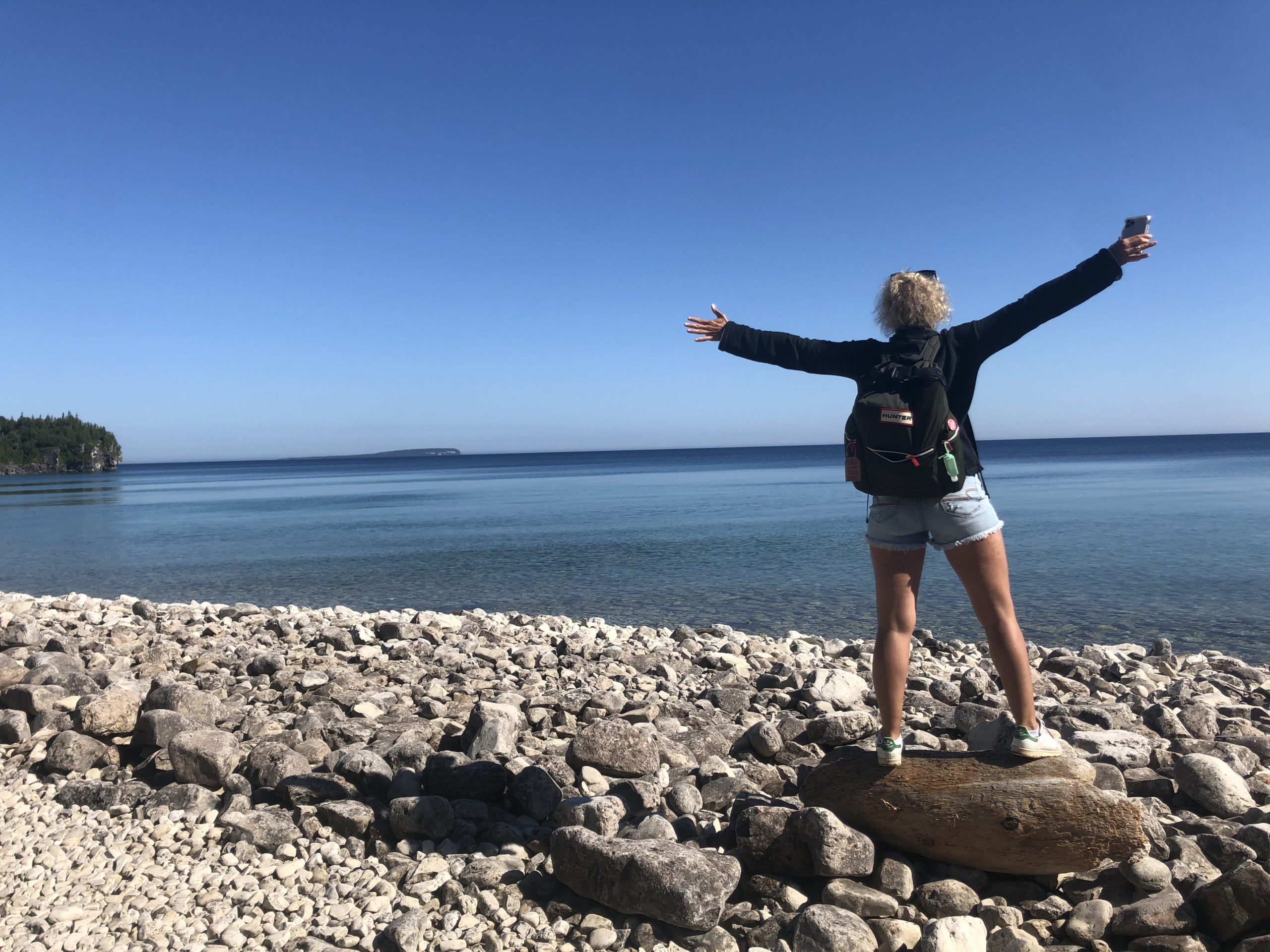 Amanda stands, arms up, on a rocky Georgian Bay beach