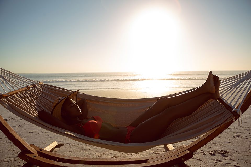 Woman sleeping in hammock on beach