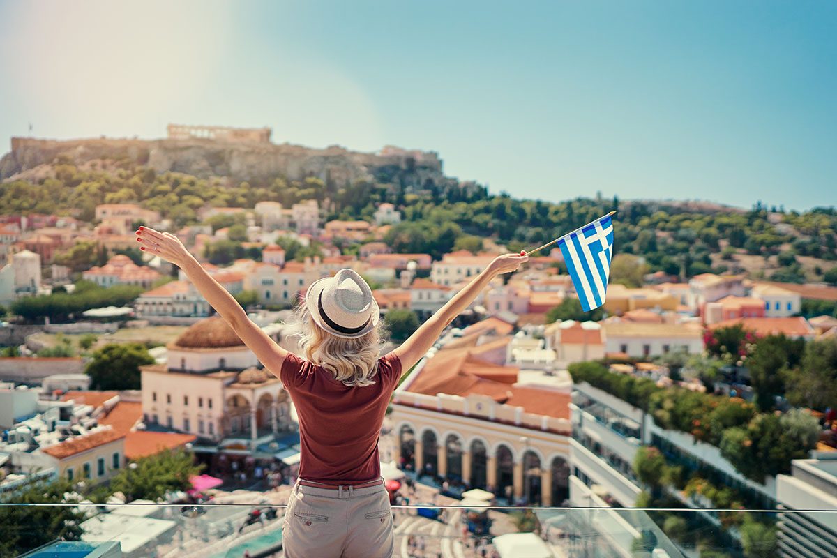 Woman with Greek flag overlooking Athens City and Acropolis