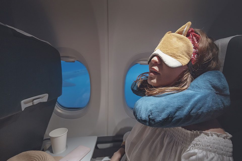 Young woman wearing eye mask sleeps on plane