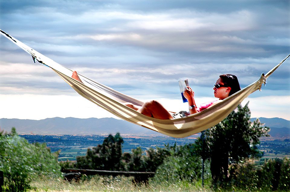 Young woman reading in a hammock in the sun
