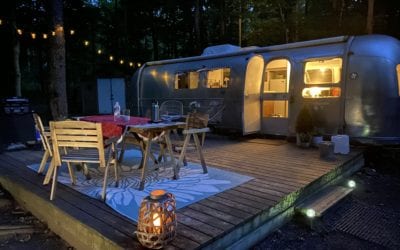 A cozy airstream with string lights and an outdoor patio table.