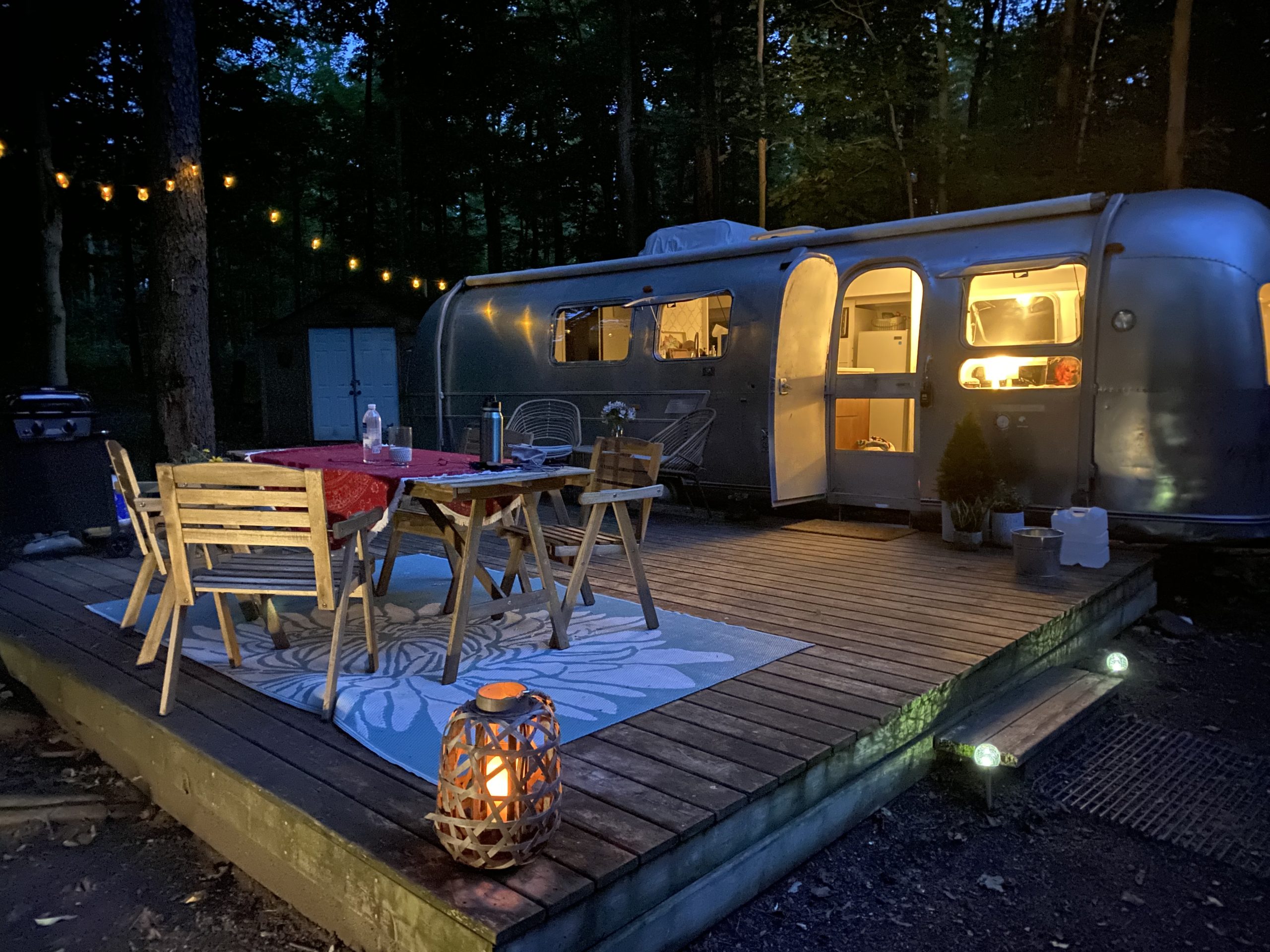 A cozy airstream with string lights and an outdoor patio table.