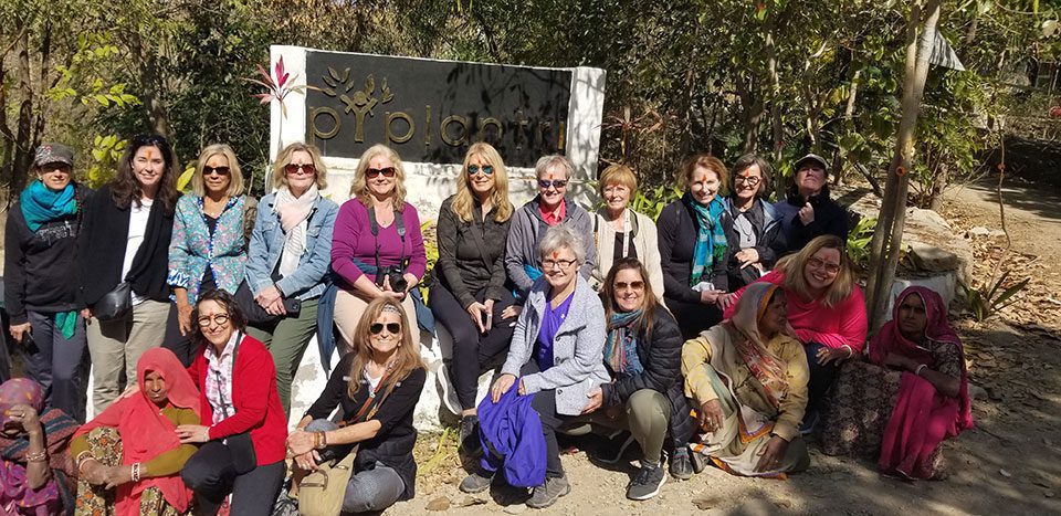 A group from Bonnie's tour sit with young women in the village