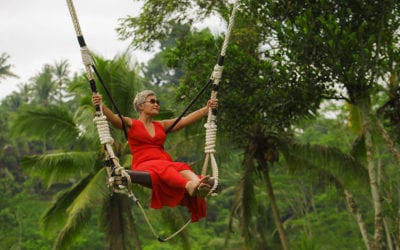 Smiling woman in bright red dress on tree swing