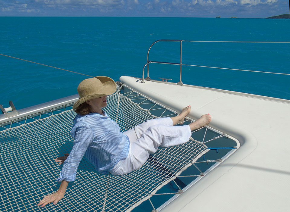 Mature woman wears sun hat on catamaran on the ocean