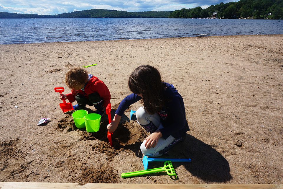 Two kids dig in the sand at Little Doe Lake in Katrine Ontario