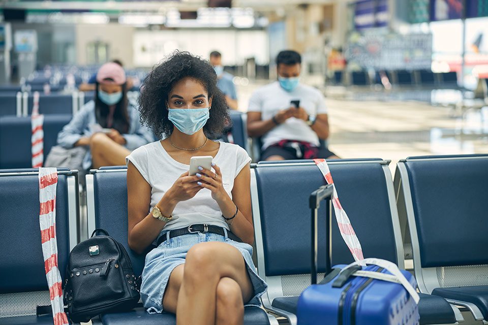 Young black woman in mask at departure lounge