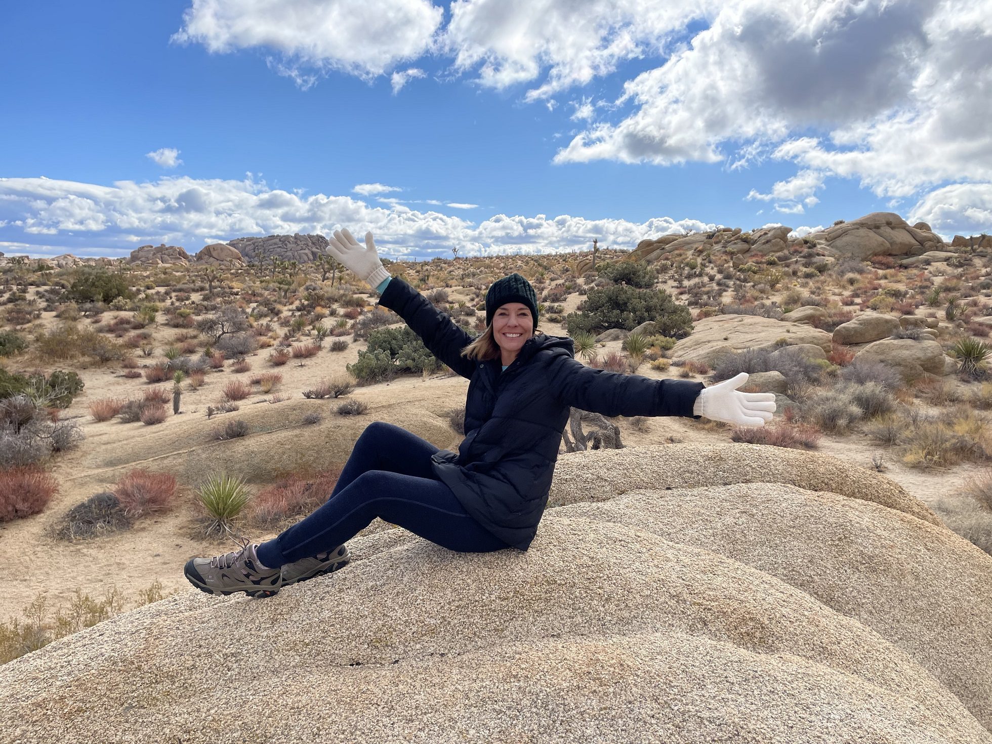 Shawna Robbins with arms stretched wide on a hilltop