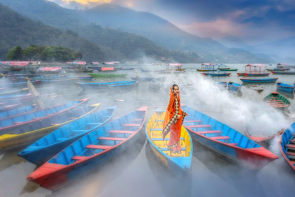 A young woman in a sari stands in a boat in Pokhara, Nepal