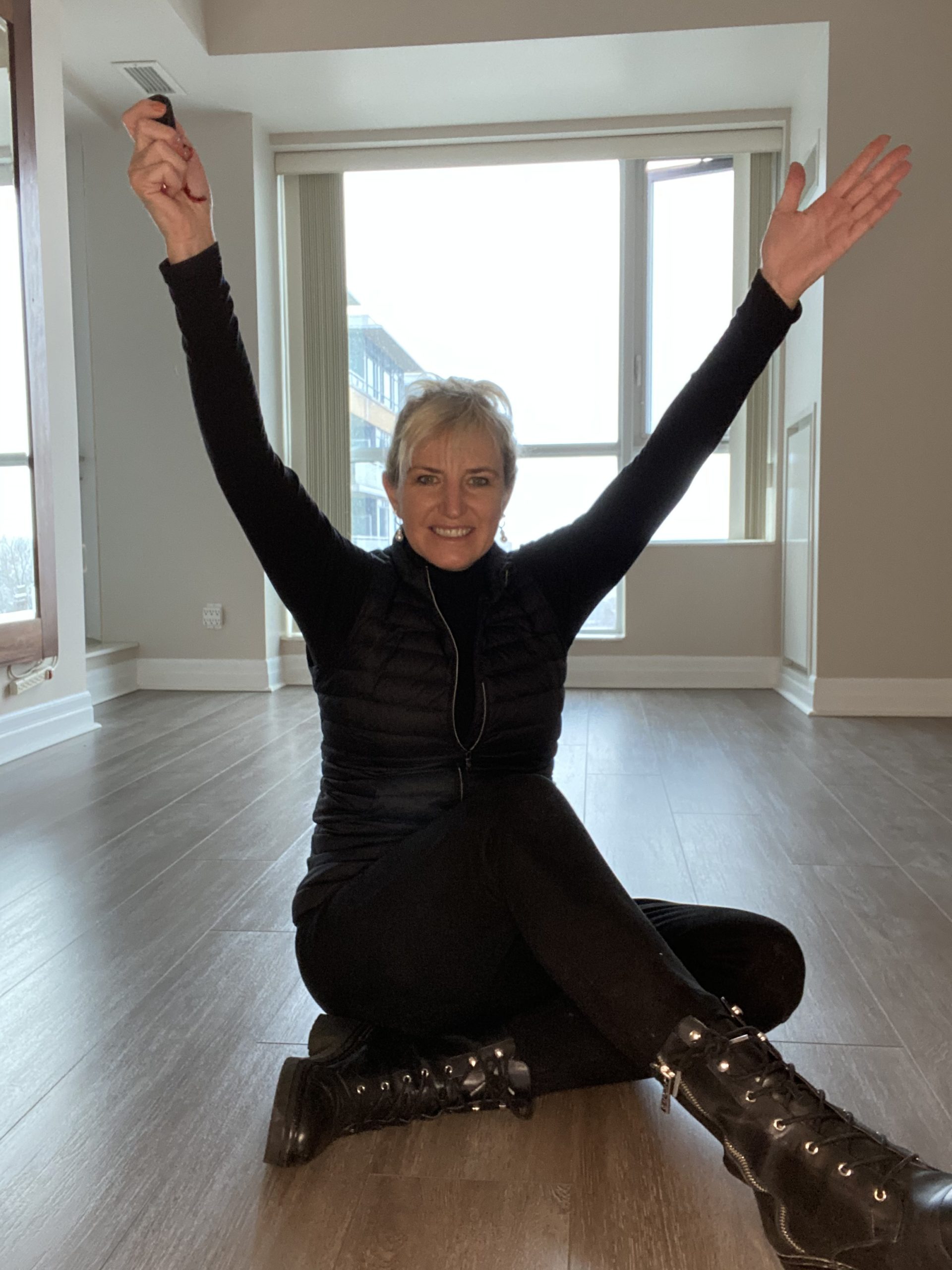 Carolyn, arms up in her freshly emptied apartment