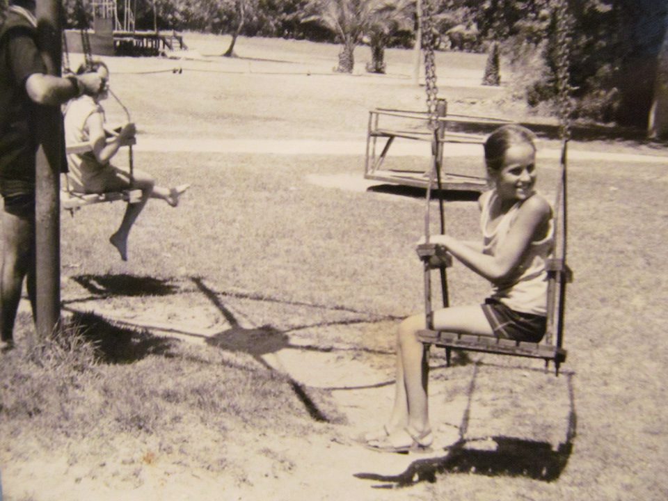 A young girl sitting on a wooden swing