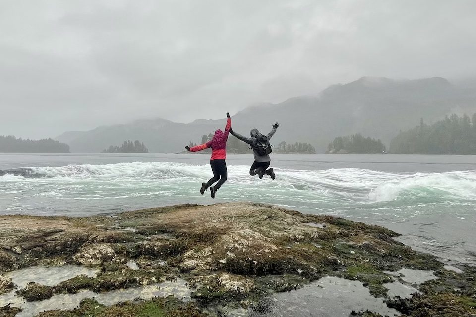 Danika and Amanda jump for joy at the awe-inspiring sight of the Skookumchuk Narrows, a big reward at the end of a long, wet hike