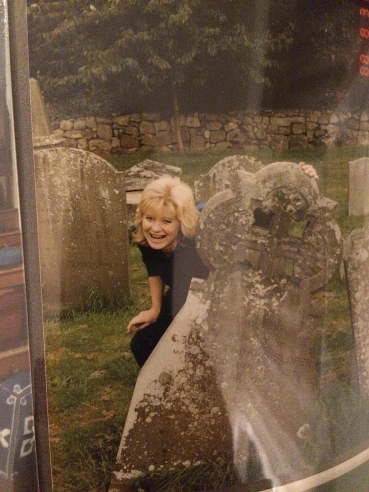 A woman peeking out from behind a rock