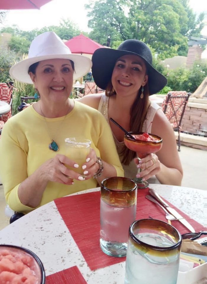Two women in hats holding a cocktail