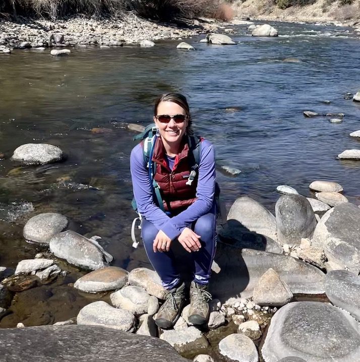 Ericka Pilcher from the National Parks Service sitting on rocks in a river
