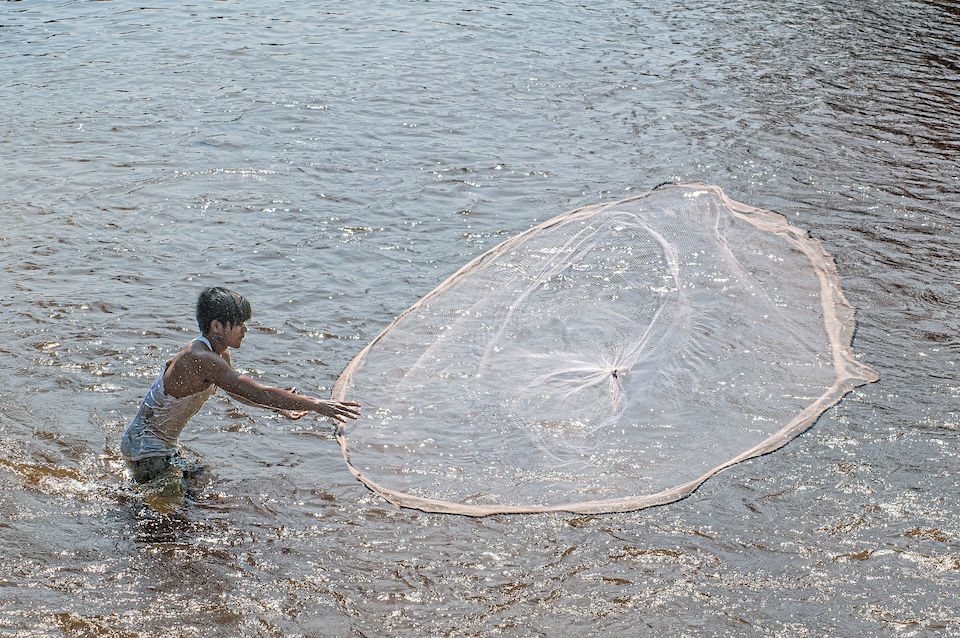 Boy fishing with a net in Cambodia | Photo by Diana Moore-Ede