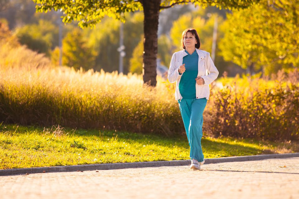 A mature woman running along a path
