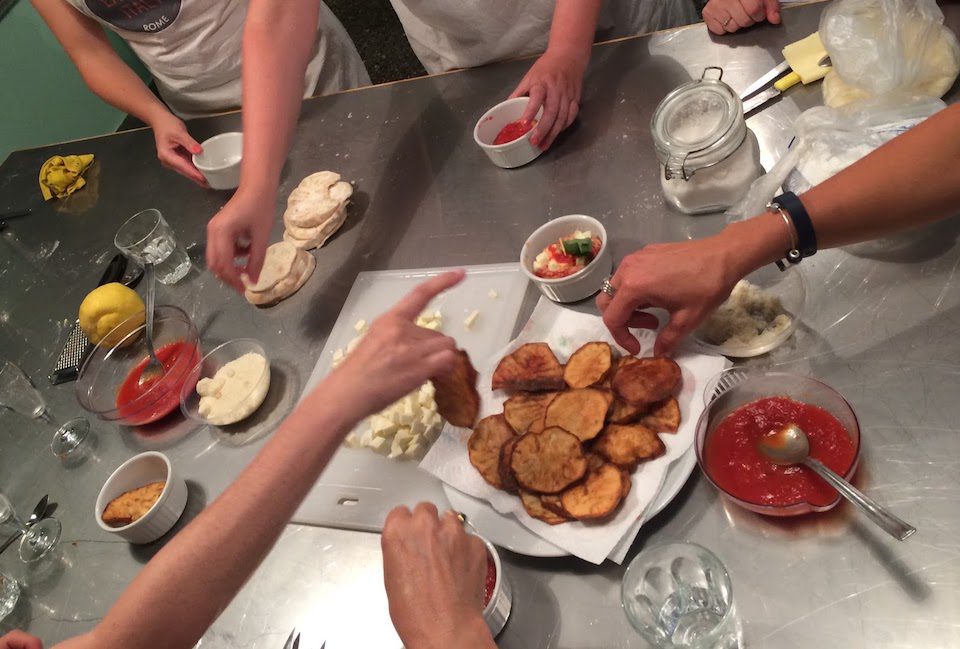 People reaching for food on a table in a cooking class in Rome