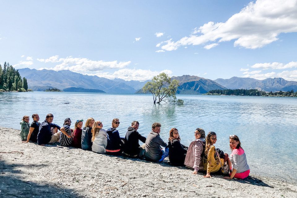 Amanda (fifth from left) and her Haka Tours crewmates on the shores of Lake Wanaka, basking in the beauty of #ThatWanakaTree, which was vandalized in March 2020