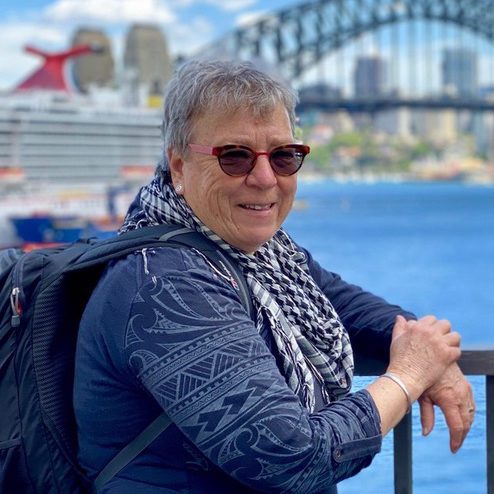 woman in blue coat in front of Sydney Harbour Bridge