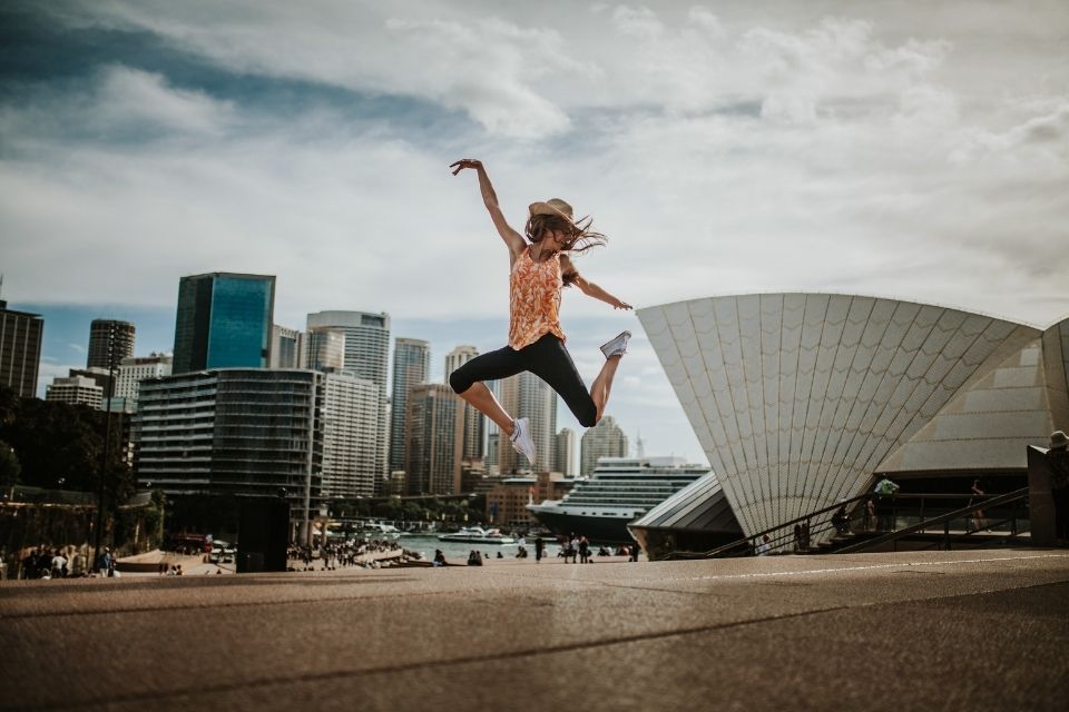 Photo of woman doing acrobatic leap in front of city skyline