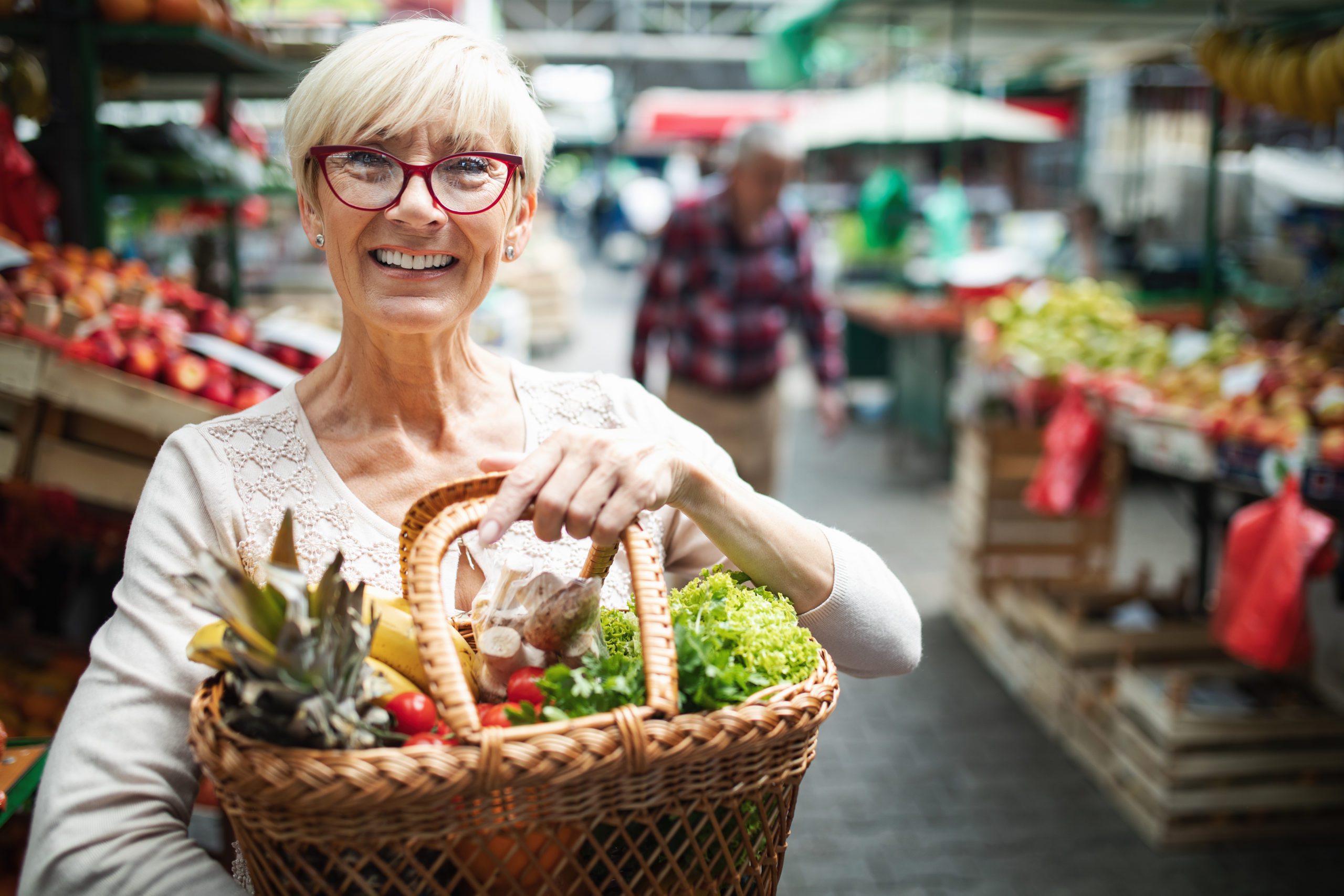 older woman holding basket of vegetables