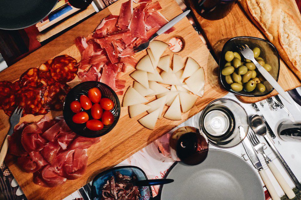 Spread of Spanish tapas including olives, cheese, and Iberian ham