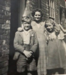Joy with her mother and brother Alan outside of the row cottage they called home in Wivenhoe