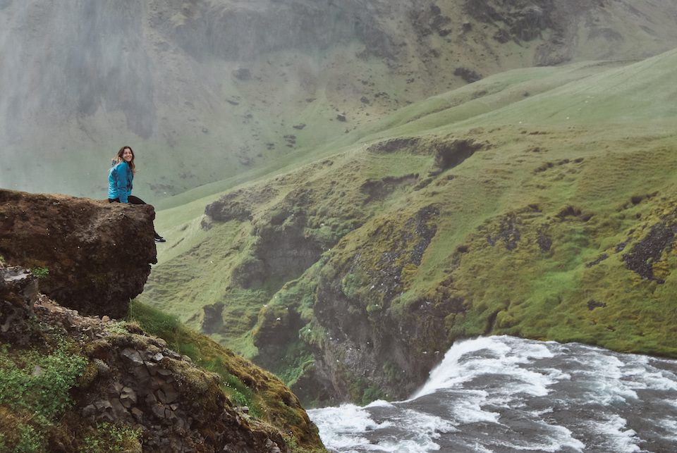 A woman sitting at the top of Skogafoss in Iceland