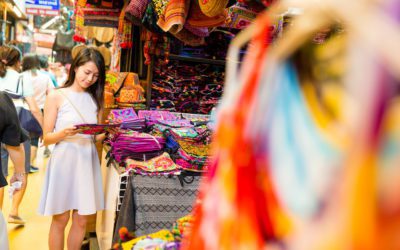 A woman shopping in a market in Thailand. Here are things women spend money on while traveling