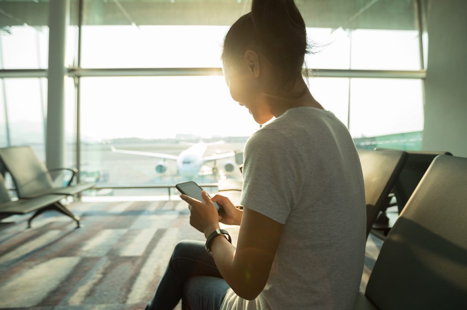 Woman passenger using mobile phone in airport