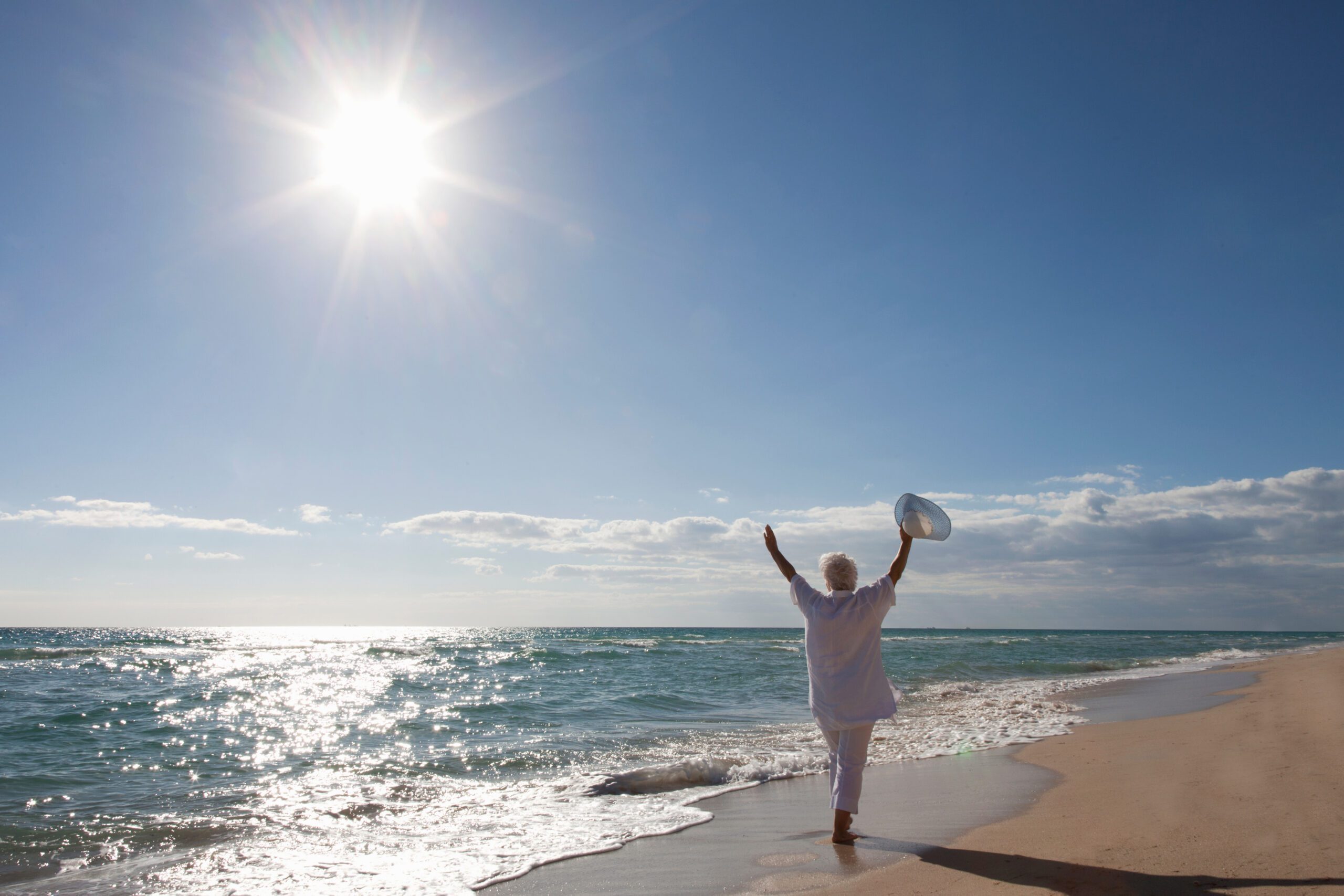 Senior Woman on the beach with her arms in the air