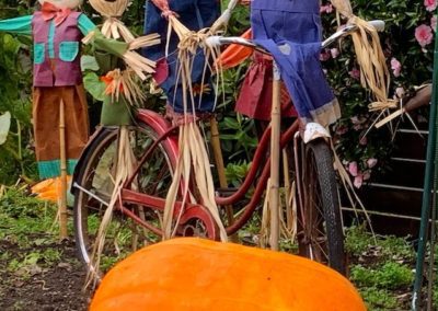 Smiling family of colourful scarecrows behind a large pumpkin