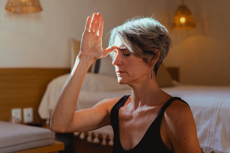A woman with her hand on her head, practising meditation