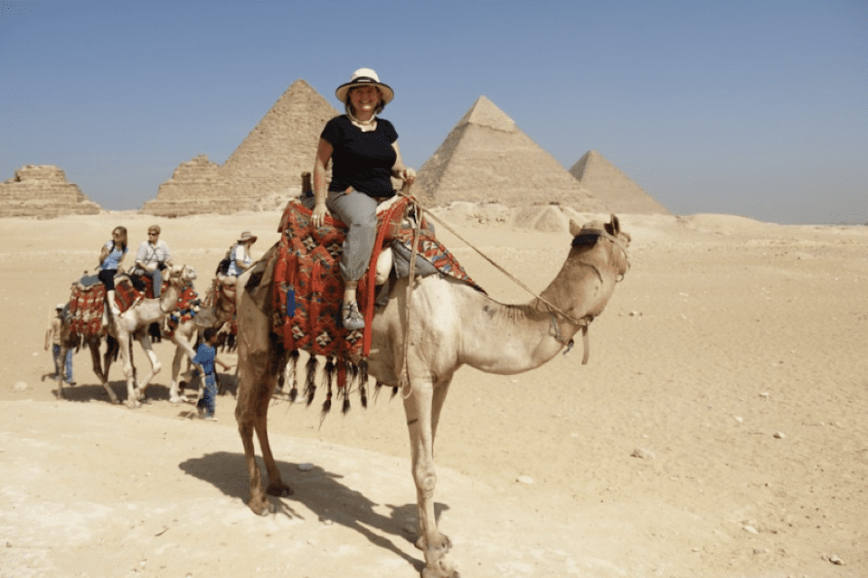 A woman on a camel in front of the Great Pyramids of Egypt