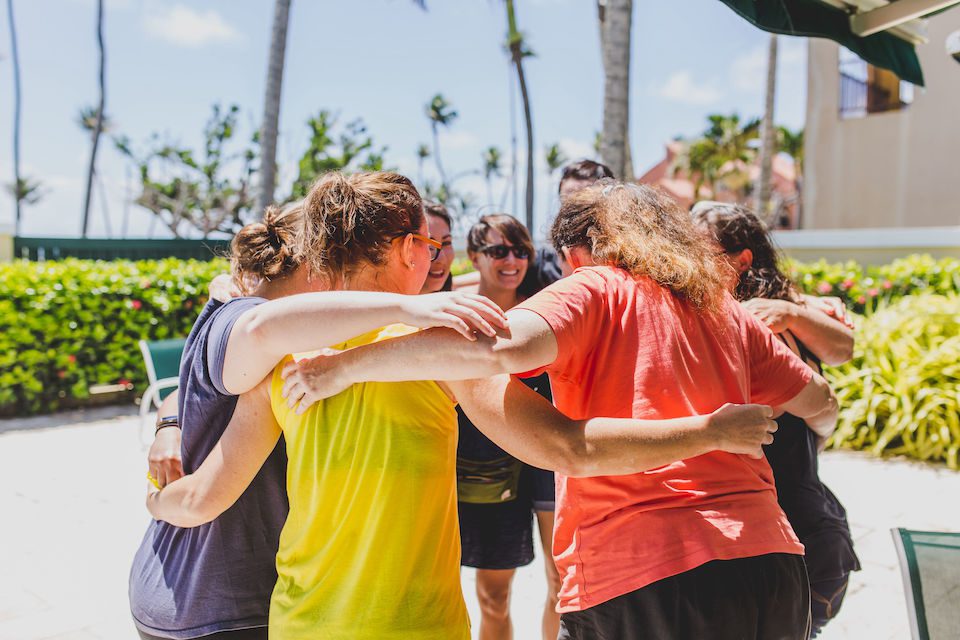 A group of women embracing in a group hug, on a transformational travel experience