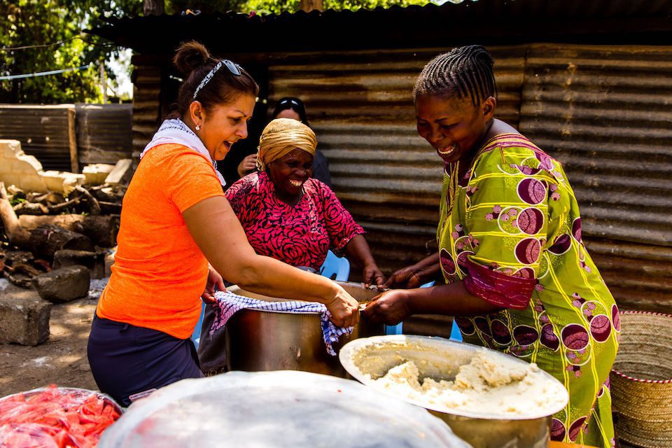 Three women working together to prepare a meal. How can women contribute to the greater good with transformative travel?