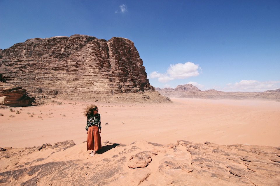 A woman standing amongst the sand in Wadi Rum Desert