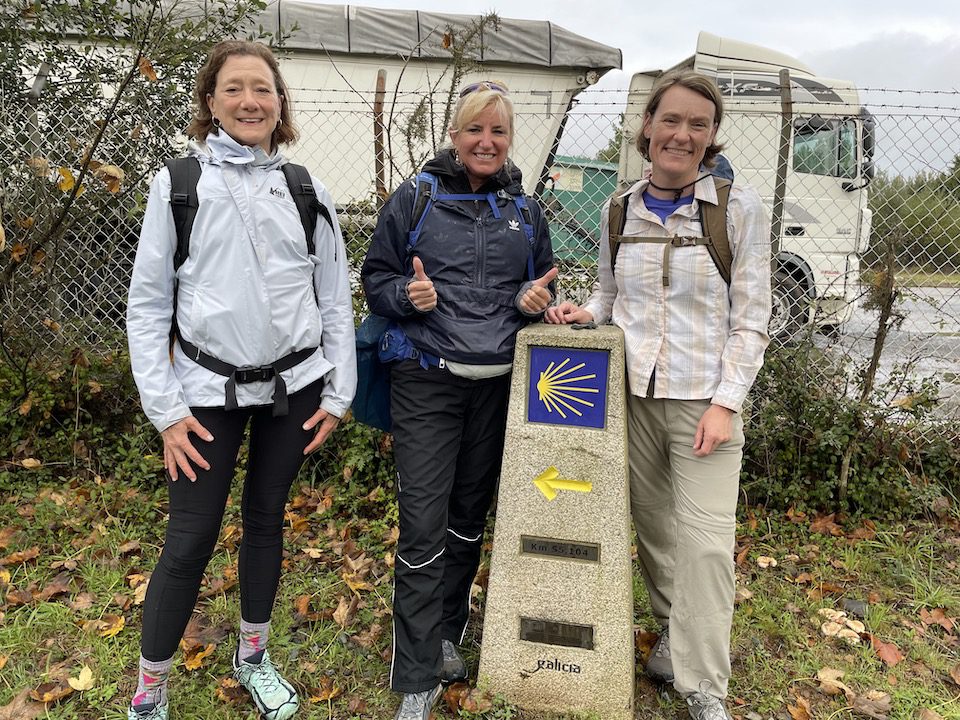Three women standing at their halfway marker along the Camino de Santiago